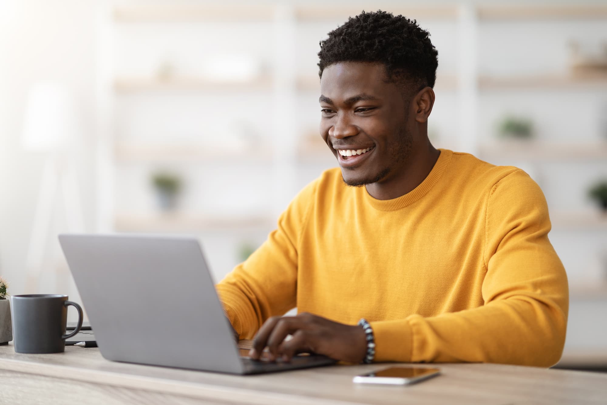 Un apprenant souriant suit une formation sur son ordinateur