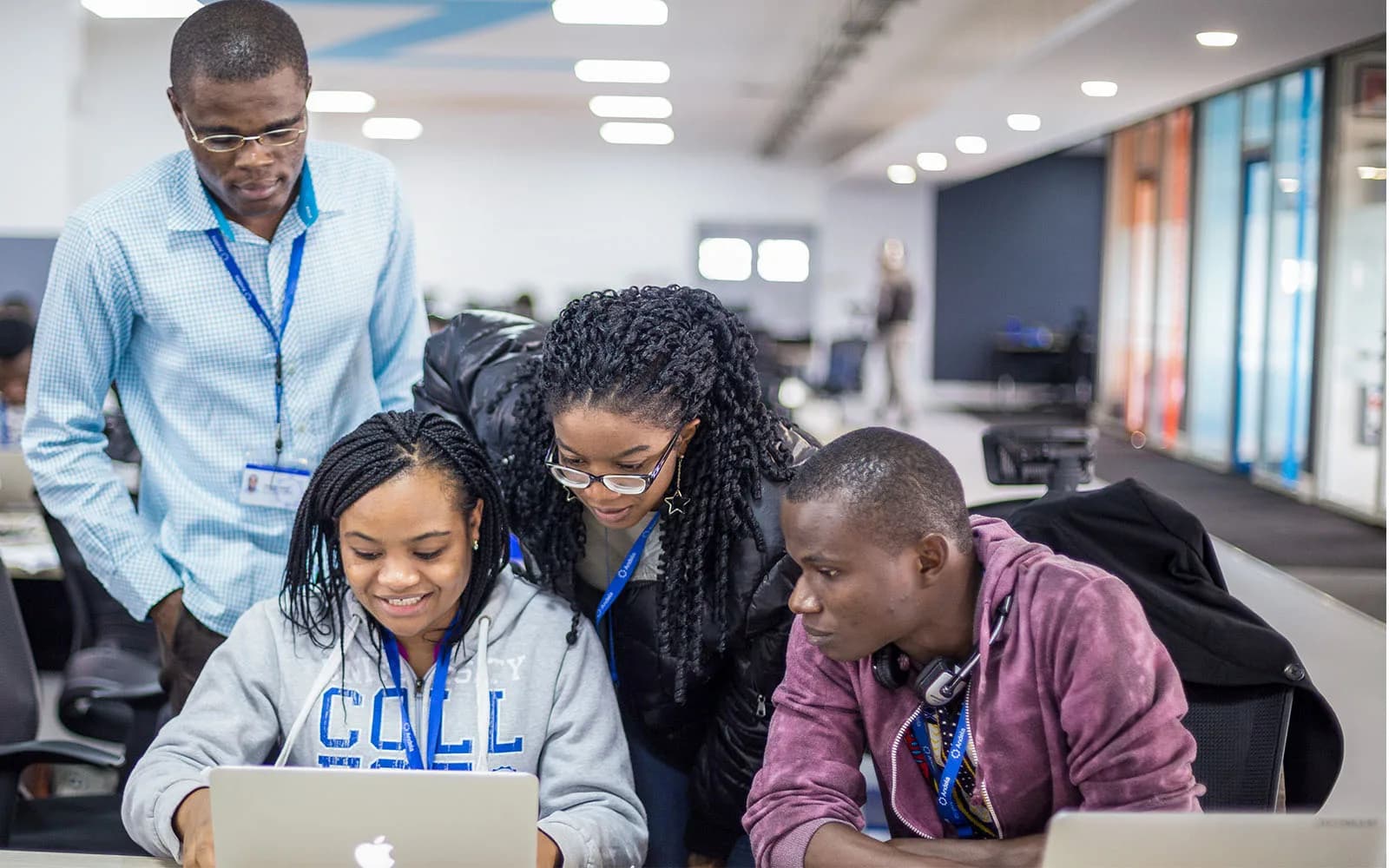 Des apprenants travaillent ensemble sur un ordinateur, accompagnés d’un formateur